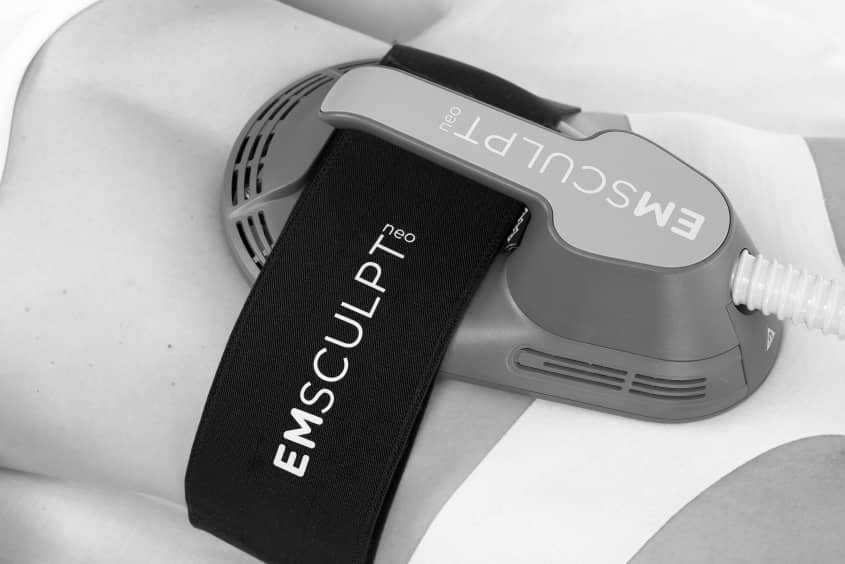 EMsculpt NEO body sculpting London - treatment applicator strapped to an abdomen in black Treatment applicator strapped to an abdomen in black and white at Square Mile Clinic, EMsculpt NEO body sculpting London